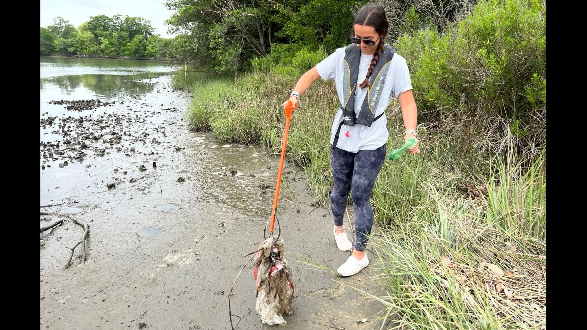 Lexi Bradshaw brings a plastic bag to the collection of litter she picked up. (Photo: Laura Philion)
