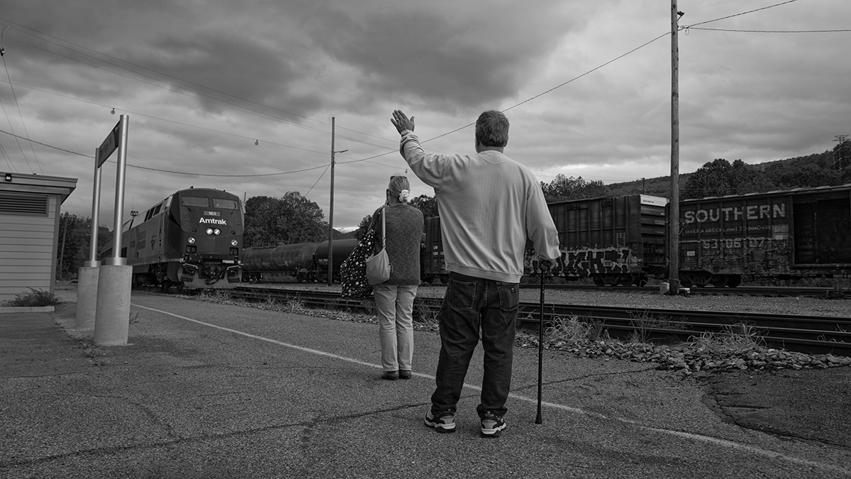 Paul Ballard waves as the Amtrak train approaches town. Ballard and his wife Donna came from their home in Boone, West Virginia, for a day trip to Clifton Forge to tour the railway musem and history records. Paul collects model trains with his friend Jim Chaney. Jim's wife Marie also made the trip. Paul's father worked on the railroad for 46 years.