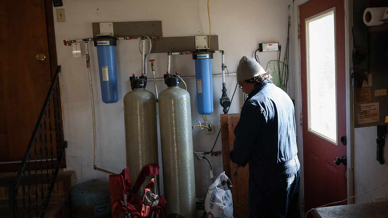 Boun Keosavang stands beside a carbon filtration system connected to his home’s well, located a few hundred yards away from Fentress Naval Auxiliary Landing Field. The filtration system was installed by the Navy in 2017. Photo taken November 17, 2022.
